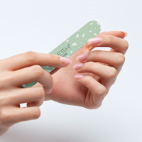 Hand using a green nail file on a light gray background
