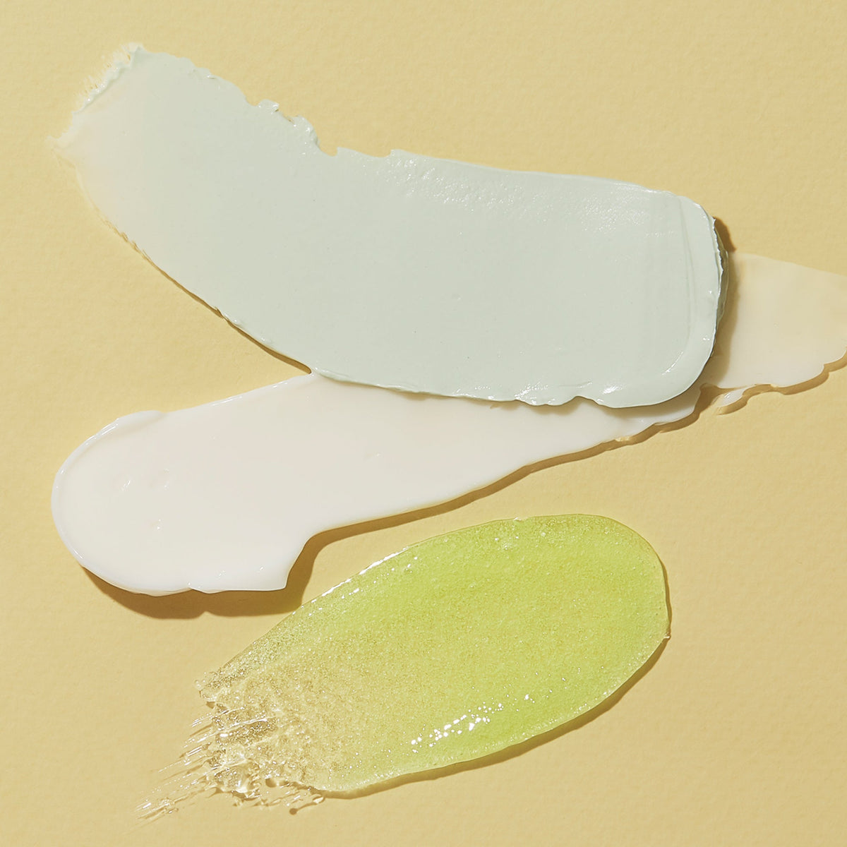Two swatches of cream, one white and one green, on a beige background